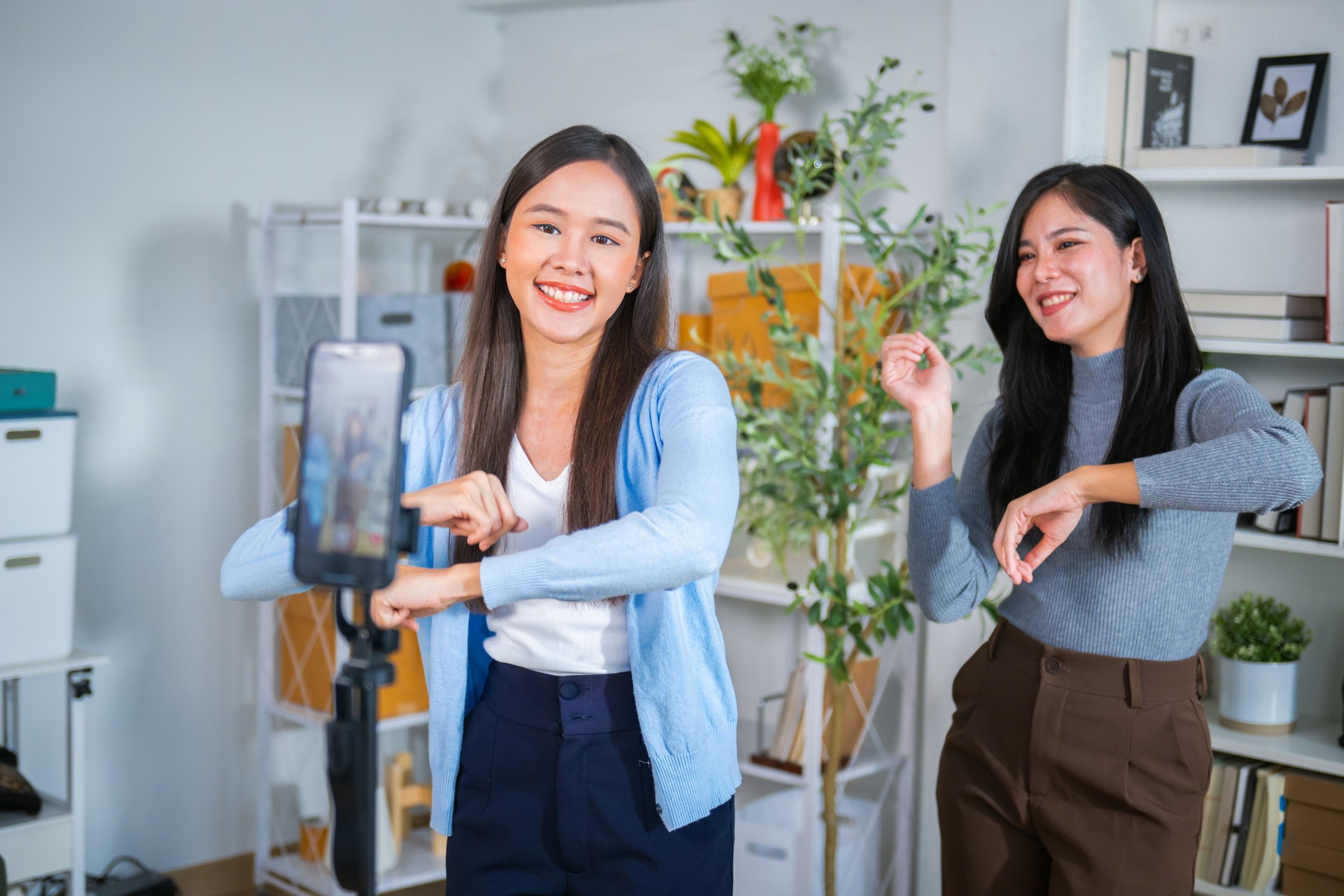 Two female salespeople are live-streaming a sale on their mobile phones on TikTok