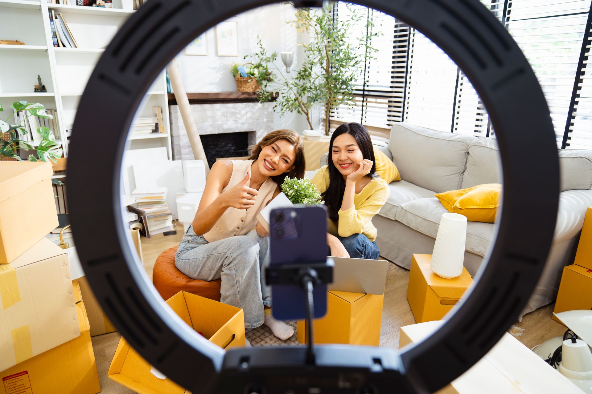Two Asian female friends are doing live streaming to sell products.